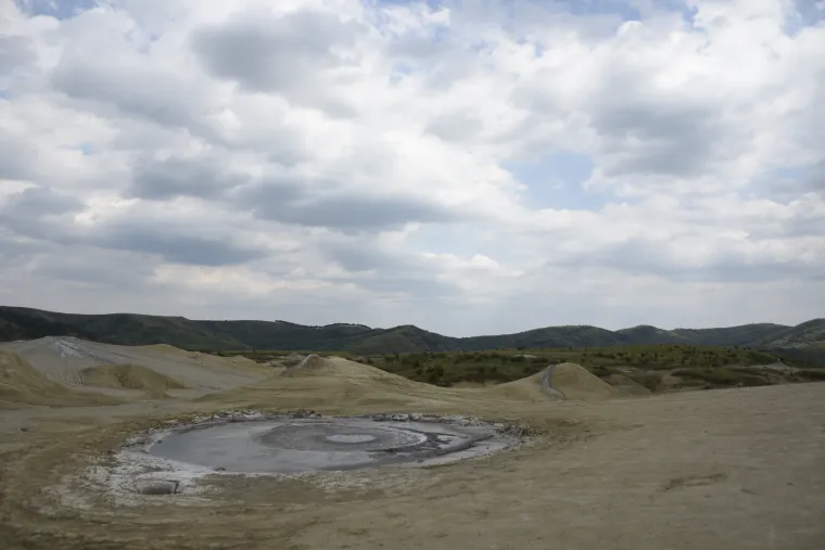 A wide mineral landscape beneath an expansive cloud-filled sky.