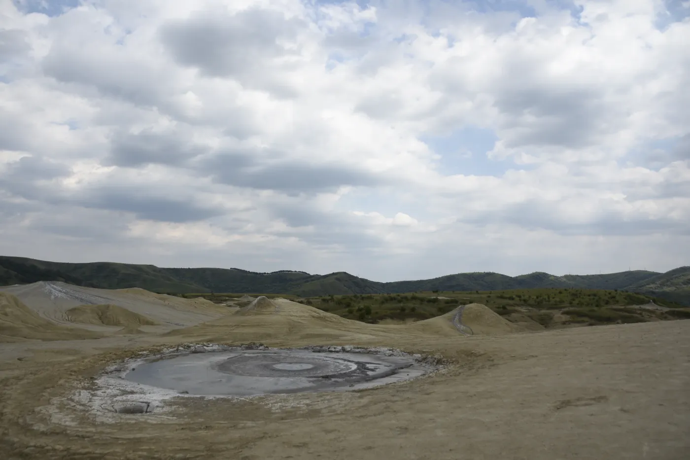 A wide mineral landscape beneath an expansive cloud-filled sky.