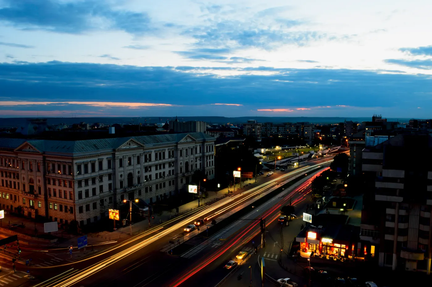 An elevated view over a city at blue hour with streaks of traffic light below.